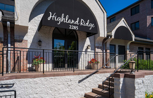 Exterior shot with stairs leading to front door and a black awning with the words "Highland Ridge 2285" written in white