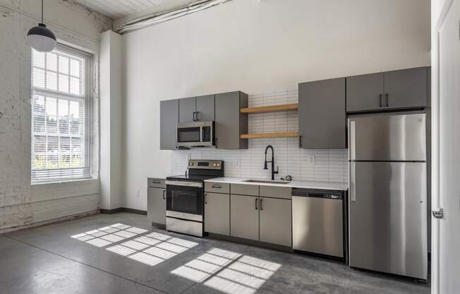 a kitchen with stainless steel appliances and a window at Highland Mill Lofts, Charlotte, North Carolina