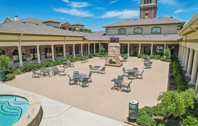 A large outdoor patio area with tables and chairs and a pool.