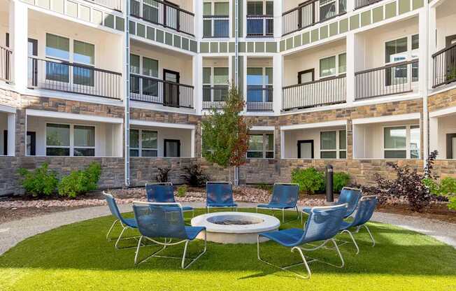 A small round table surrounded by blue chairs in front of a building.