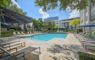 A pool surrounded by sun loungers and umbrellas.