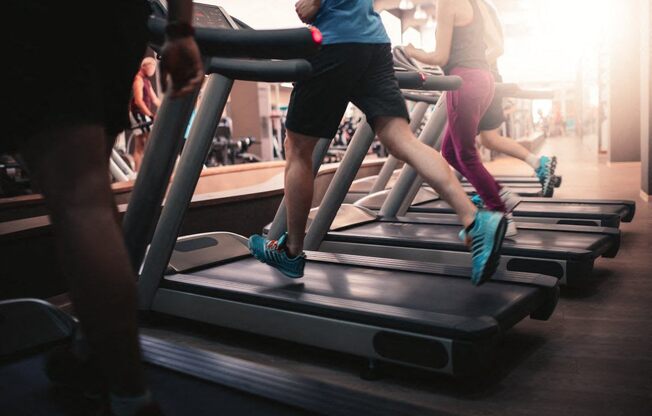 A group of people are exercising on treadmills in a gym.