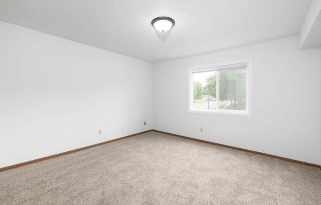 A room with a carpeted floor and a window.