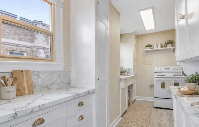 A kitchen with white cabinets and a marble countertop.