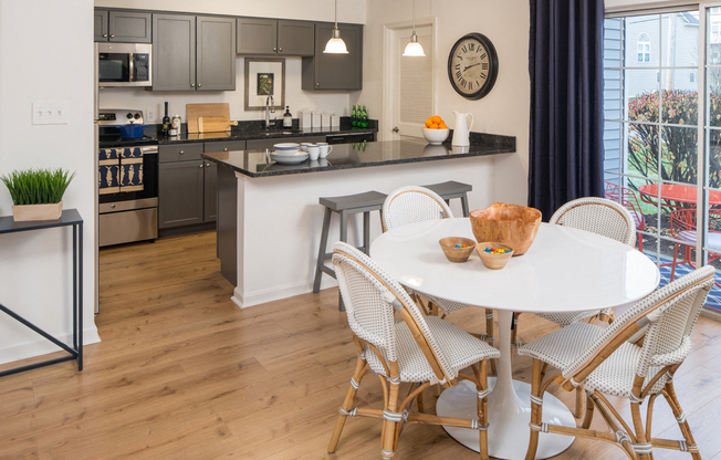 Kitchen and dining area with dark cabinets, granite counters, and a round dining table