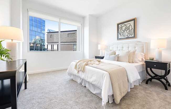 A bedroom with a large bed and a window overlooking a building.