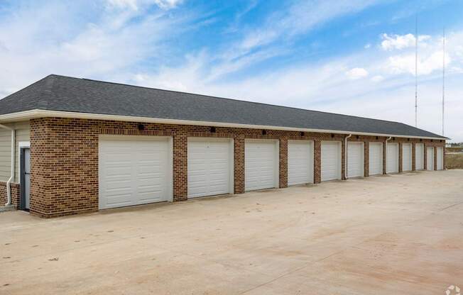 A long building with a grey roof and white garage doors.