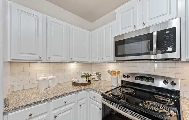 a kitchen with white cabinets and a stove and microwave