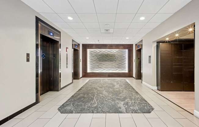 A hallway with a marble rug in the middle and a glass wall in the background.