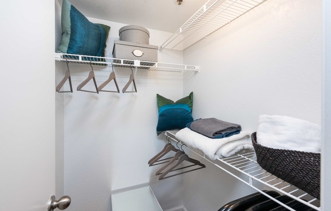 a laundry room with a chair and a shelf with towels on it