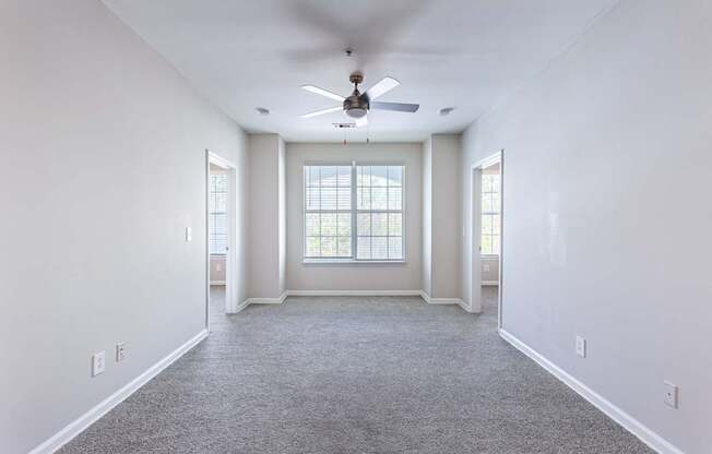 A spacious room with a ceiling fan and carpeted floor.