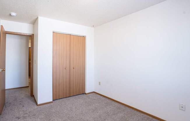 A room with a brown door and carpeted floor. Fargo, ND Country Edge Apartments