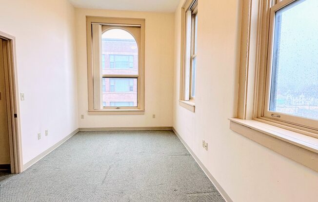 a room with a carpeted floor and two windows