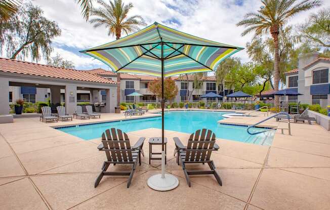 A pool with a striped umbrella and chairs.