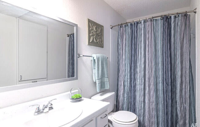 a white bathroom with a shower curtain and a sink