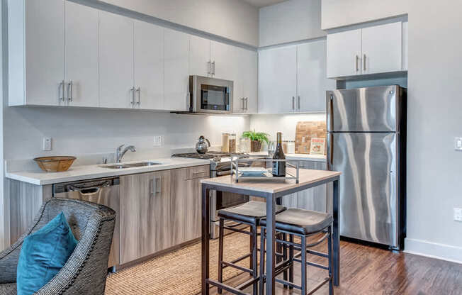 A kitchen with a refrigerator, sink, and bar stools.