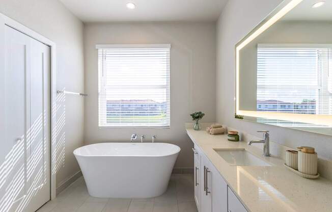 A white bathroom with a tub, sink, and a window.