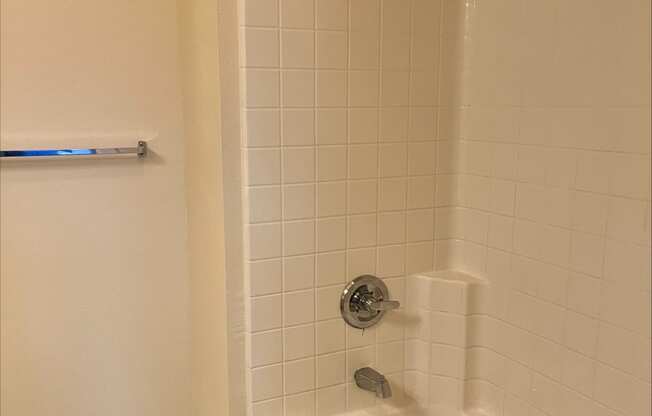 a bathtub with white tile and a shower head