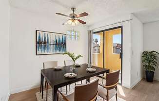 A dining room with a table set for two and a ceiling fan.