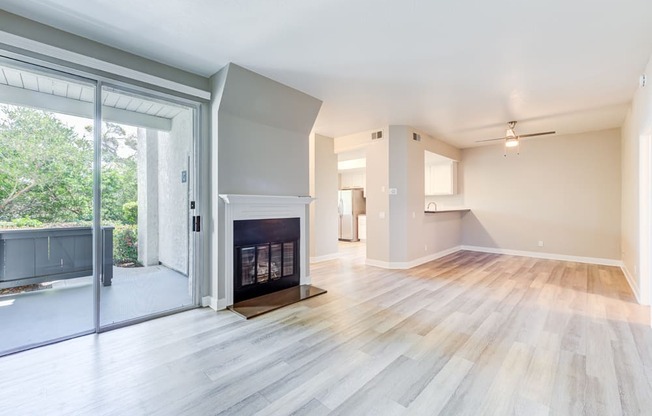 an empty living room with a fireplace and a sliding glass door