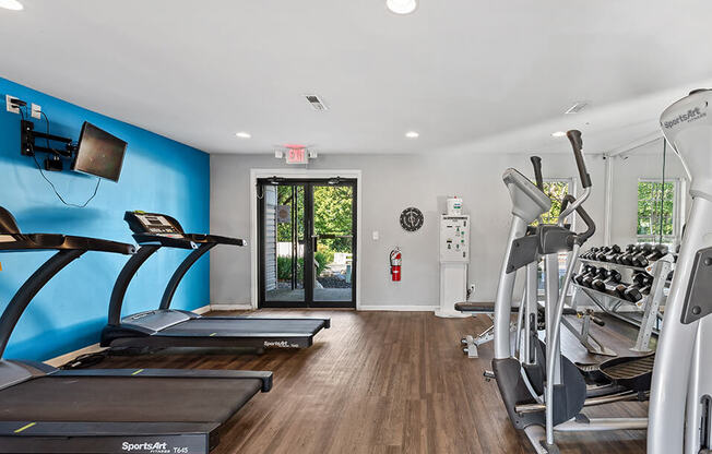 a gym with cardio equipment and a blue wall