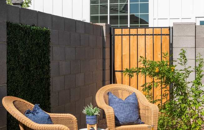 a backyard patio with two rattan chairs and a coffee table