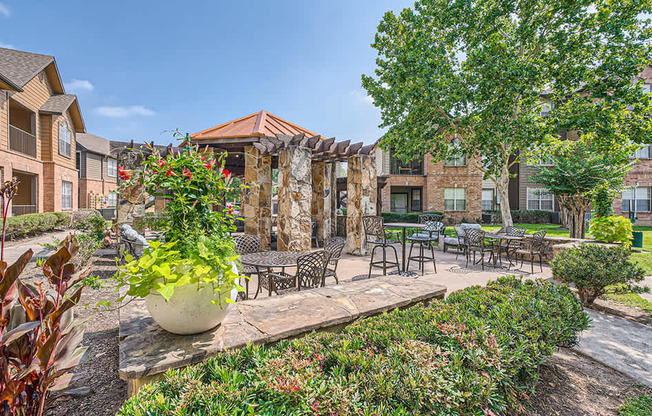 A patio area with a table and chairs surrounded by green plants.