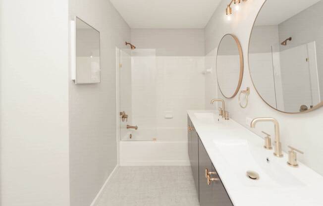 a white bathroom with a shower and a sink and a mirror