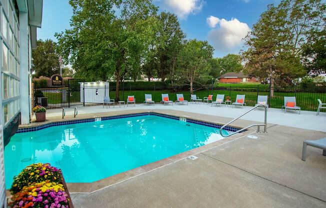 A pool surrounded by trees and chairs.