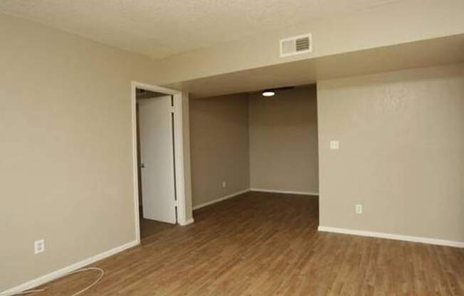 an empty living room with a wooden floor and a door