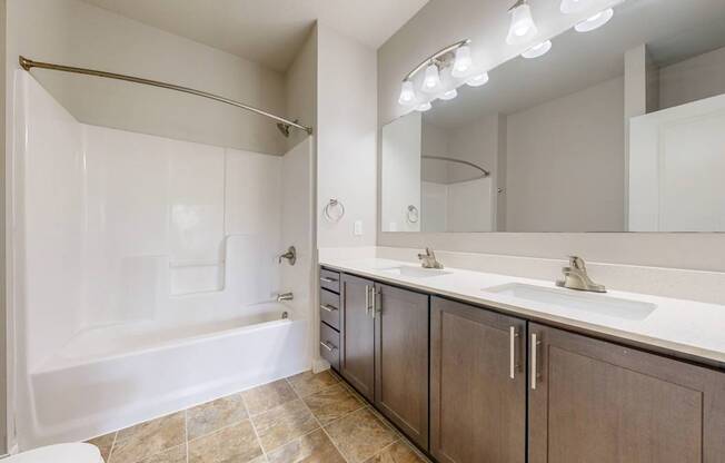 A bathroom with a white tub, sink, and mirror.