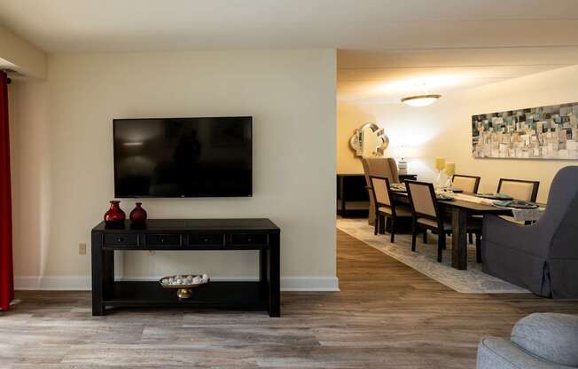 A black coffee table with a TV above it and a red vase on it.