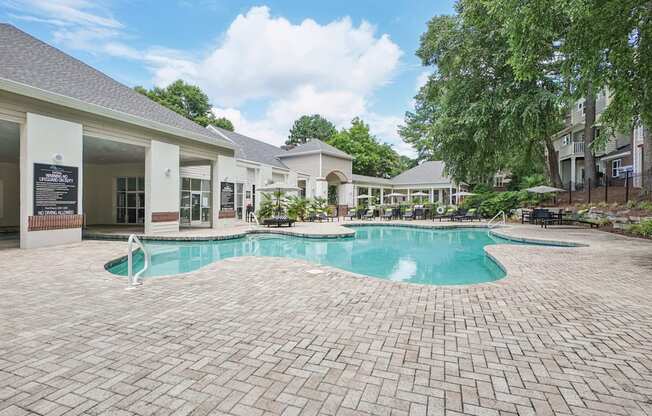 A large outdoor swimming pool surrounded by a brick patio at The Falls Apartments in Raleigh NC