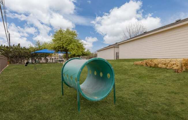 a backyard with a green play area and a green hoop in the grass