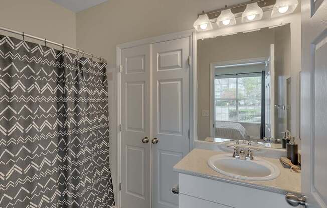 A bathroom with a sink, mirror, and shower curtain.