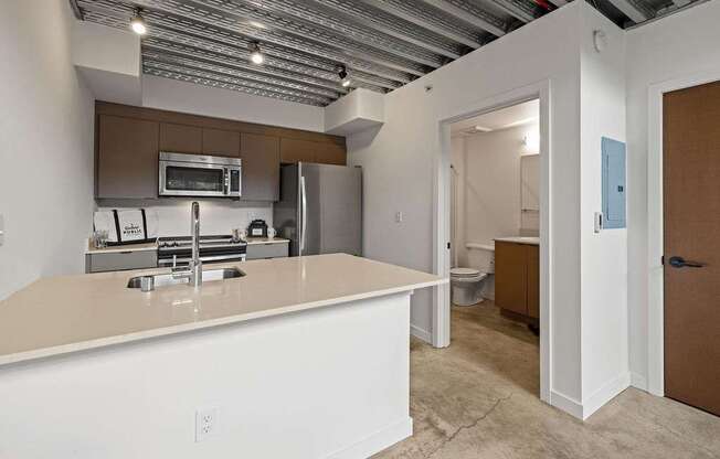 A kitchen with white countertops and a brown cabinet.