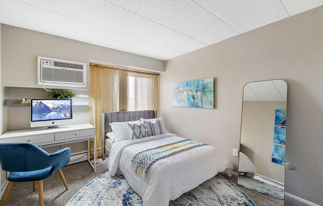 a bedroom with a bed and a desk with a mirror at Troy Place Apartments - Troy, MI, Troy, 48084