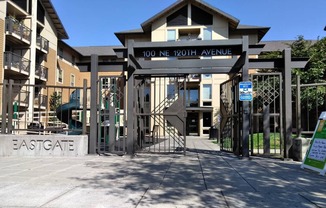 a gate is open in front of a building with a playground in the background