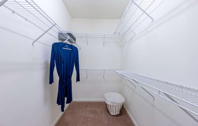 a walk in closet with a dress hangar and a trash can