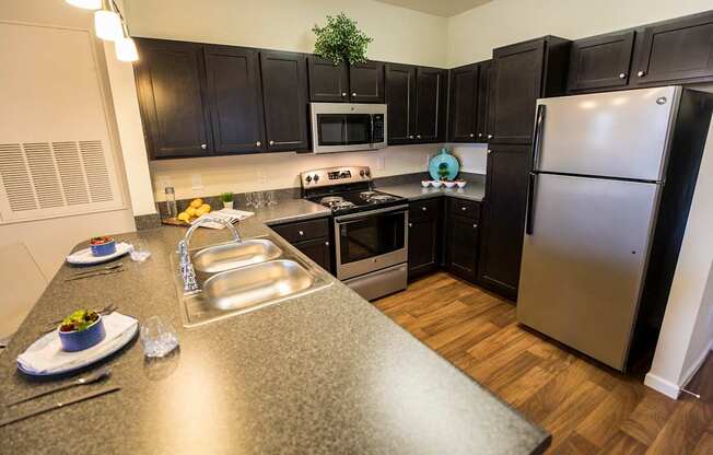 A kitchen with black cabinets and a stainless steel refrigerator.