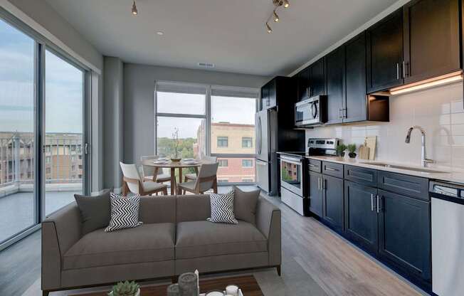 A modern kitchen with a grey couch and a dining table.