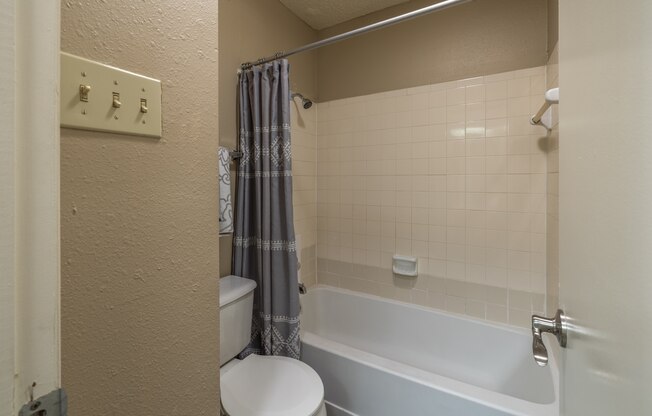 A white toilet sits next to a bathtub in a bathroom.