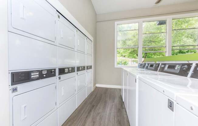 A row of white washing machines in a laundry room.