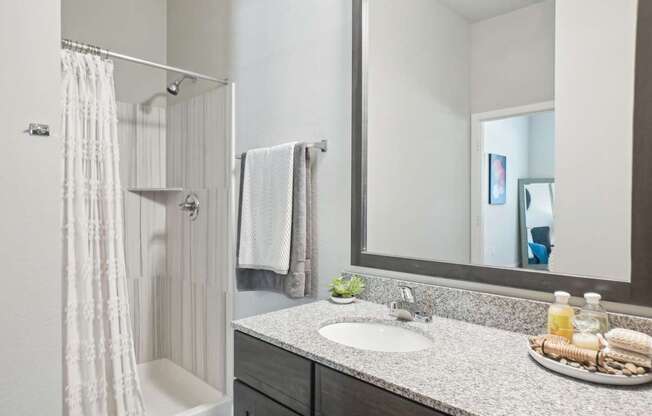 A bathroom with a white shower curtain and a white towel hanging on the shower rod.