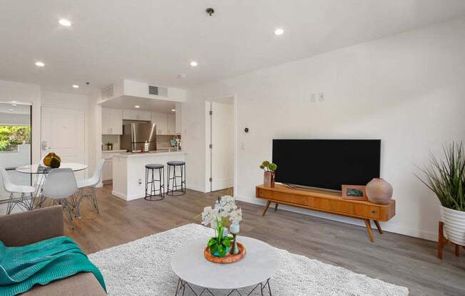 a living room with a television and a kitchen in the background  at Masselin Park West, California