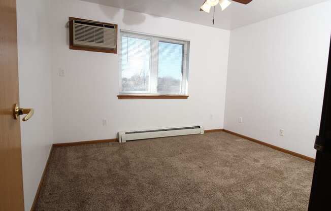 an empty room with a ceiling fan and a window