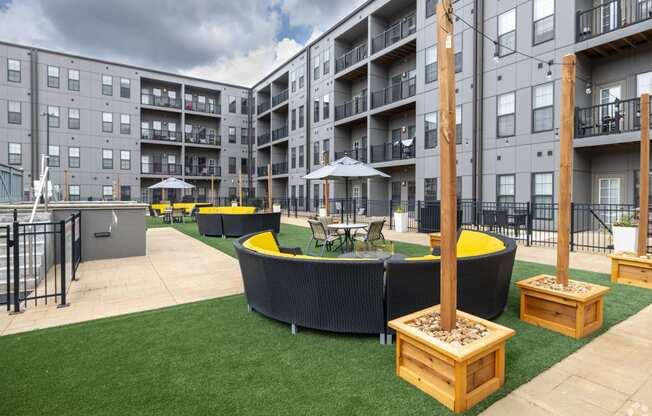 an outdoor lounge area with tables and chairs in front of an apartment building