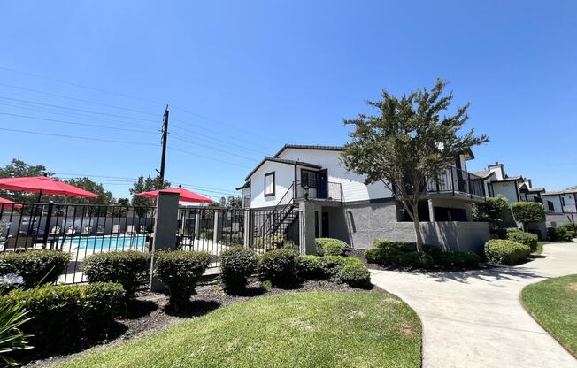 a swimming pool in front of a house with umbrellas