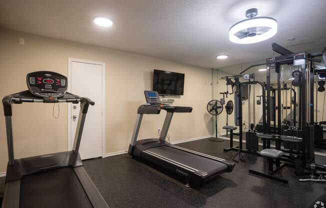 a gym with exercise equipment and a tv on the wall