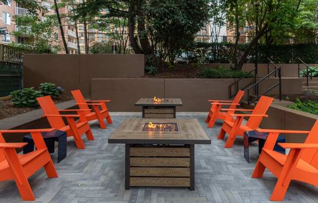 an outdoor patio with a fire table and orange chairs